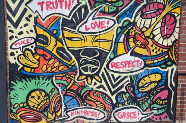 A vibrant mural featuring colorful designs with words like 'Truth!', 'Love!', 'Respect!', 'Peace!', 'Kindness!', and 'Grace!' integrated into the artwork.
